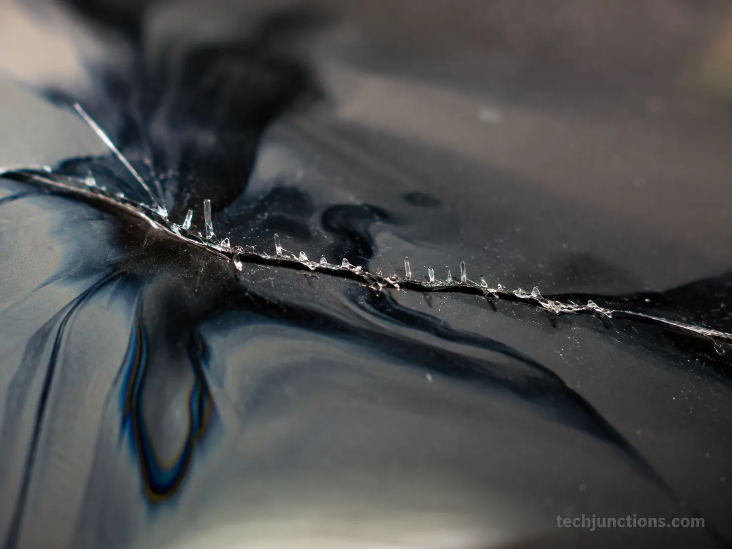 Close-up of a cracked TV panel showing sharp glass and liquid-crystal spread.