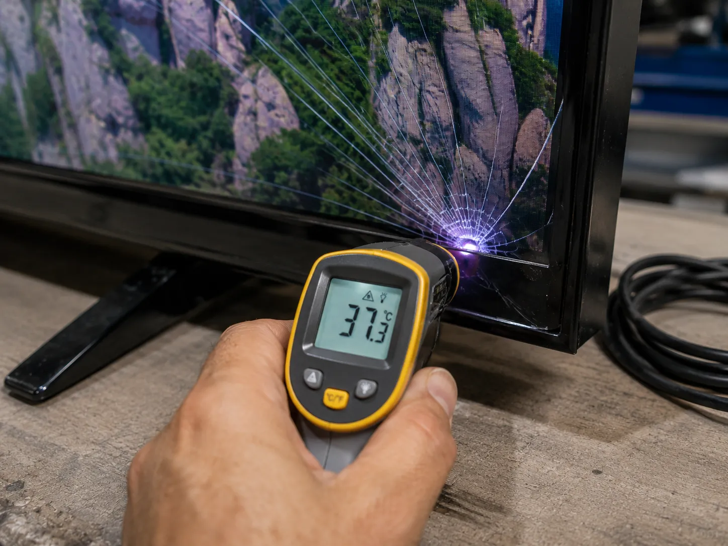 Thermometer reading the surface temperature of a cracked TV panel.