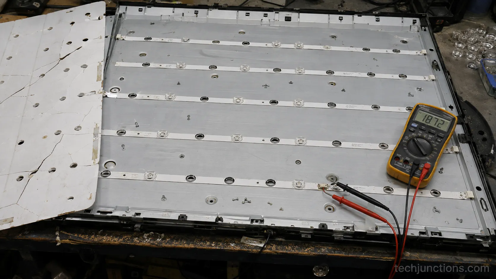Multimeter testing a failed LG TV LED strip on a scrapped panel.
