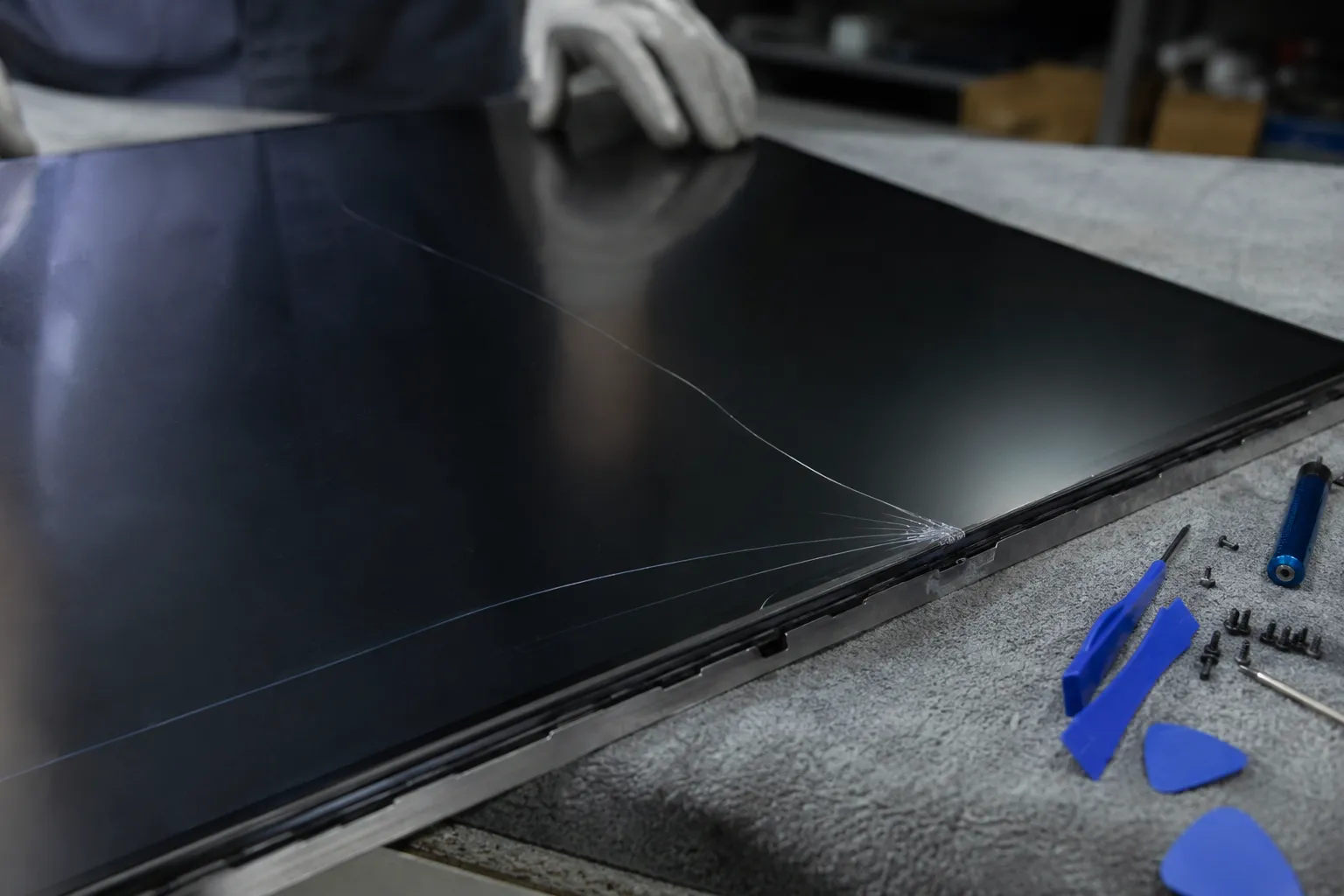 Corner-cracked Samsung replacement panel on a workbench during a DIY swap