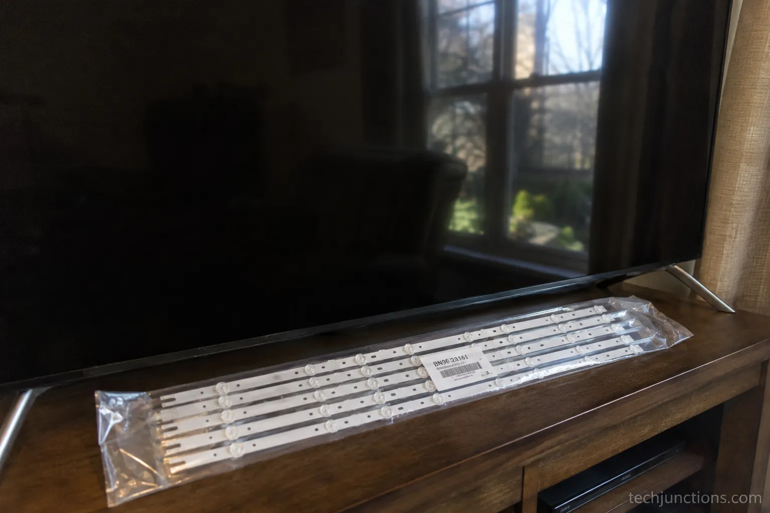 Samsung TV backlight replacement LED strip set next to a dark Samsung TV