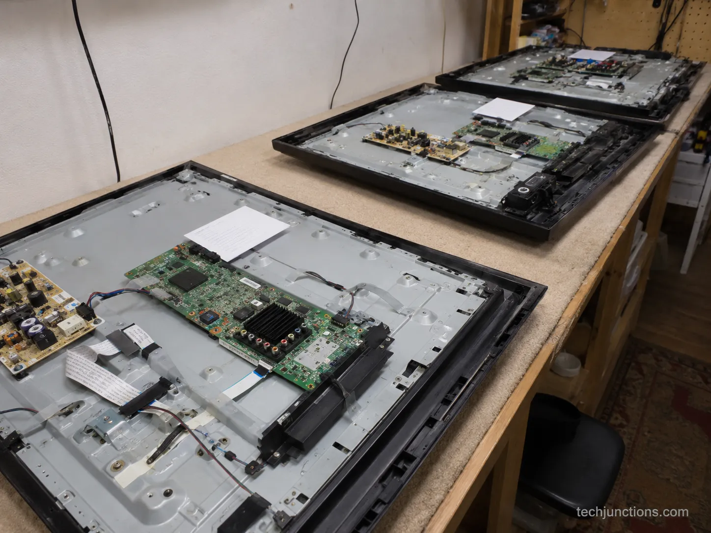 Three opened TVs on a workbench during a repair diagnosis session