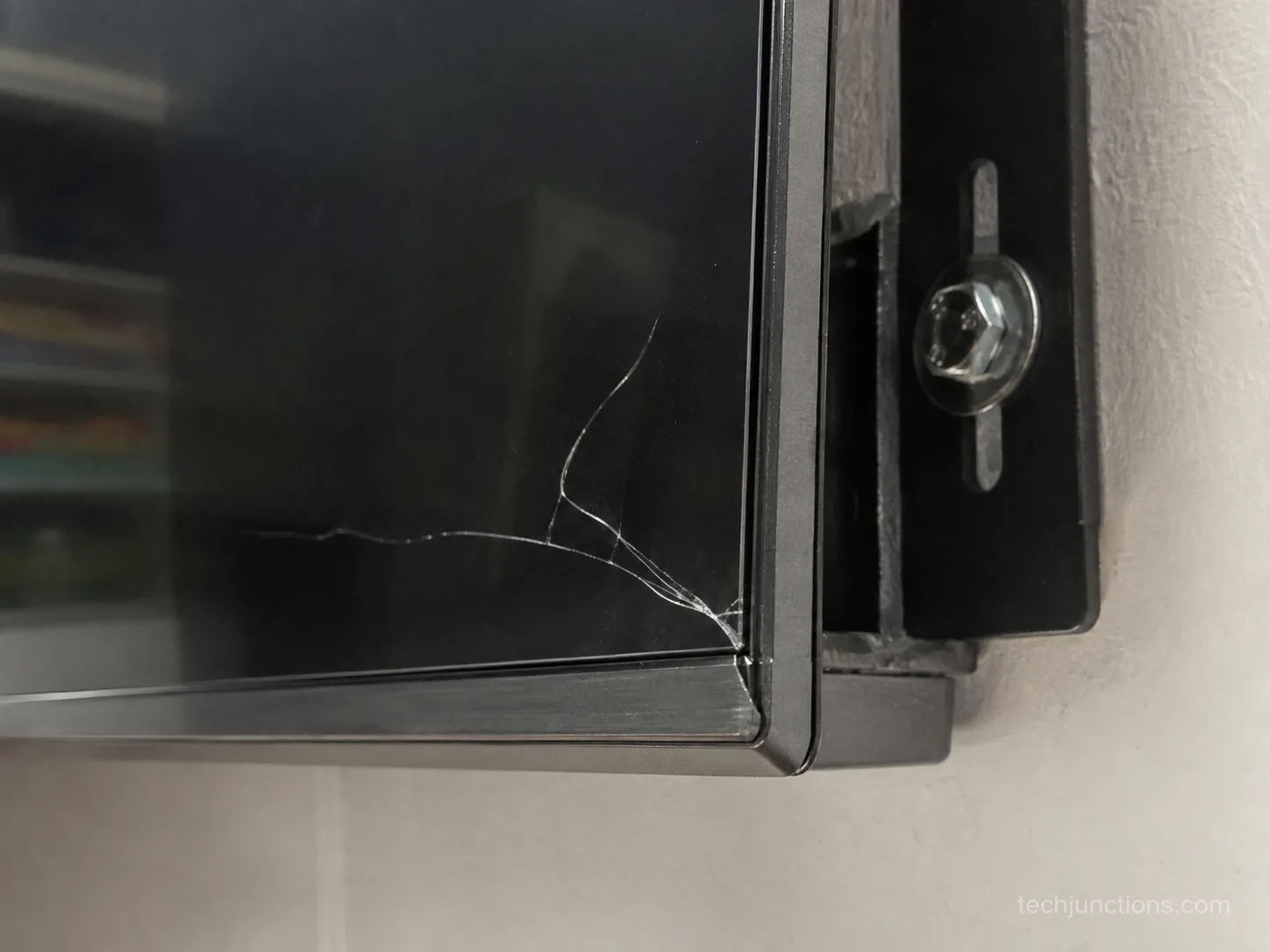 internal TV screen crack near a wall-mount bracket caused by over-tightened mounting screws.