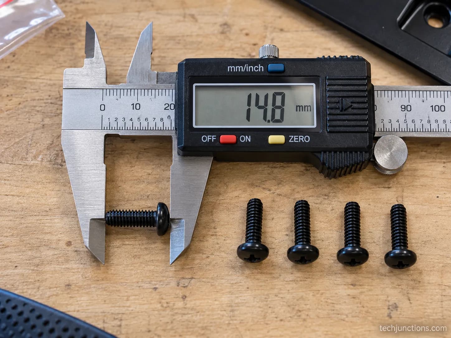 Digital calipers measuring an M4 LG TV stand screw with more stand screws arranged in a row beside it.
