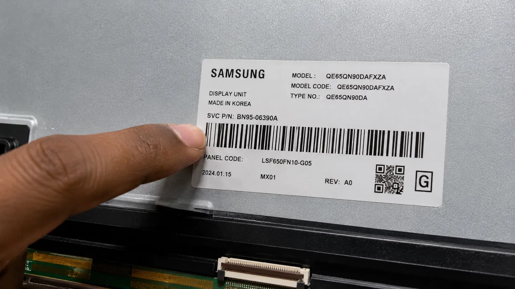 Hand pointing to a Samsung TV panel part-number sticker with a BN95 code.