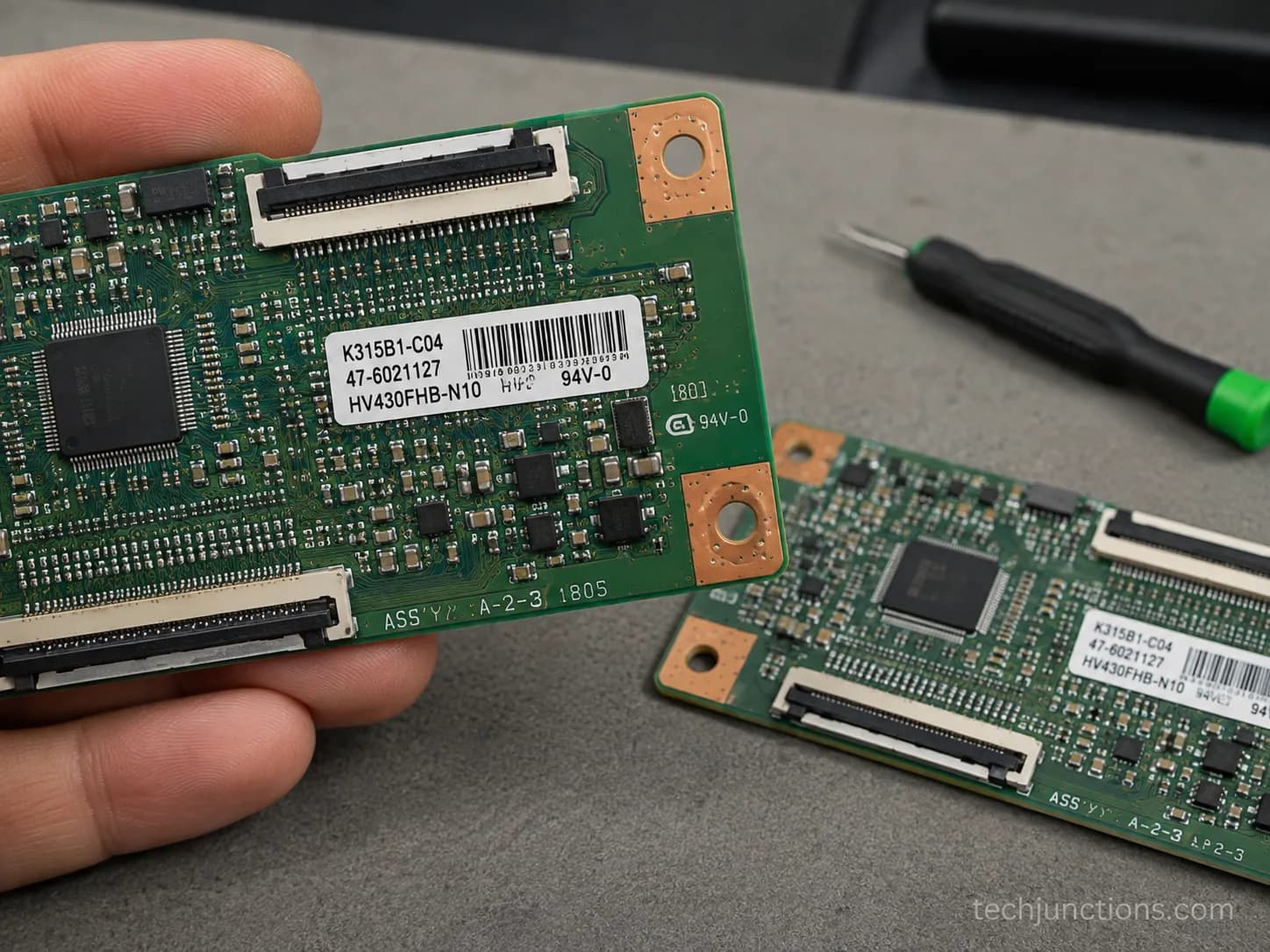 Close-up of a TV T-Con board part-number sticker next to a matching replacement board on a workbench.