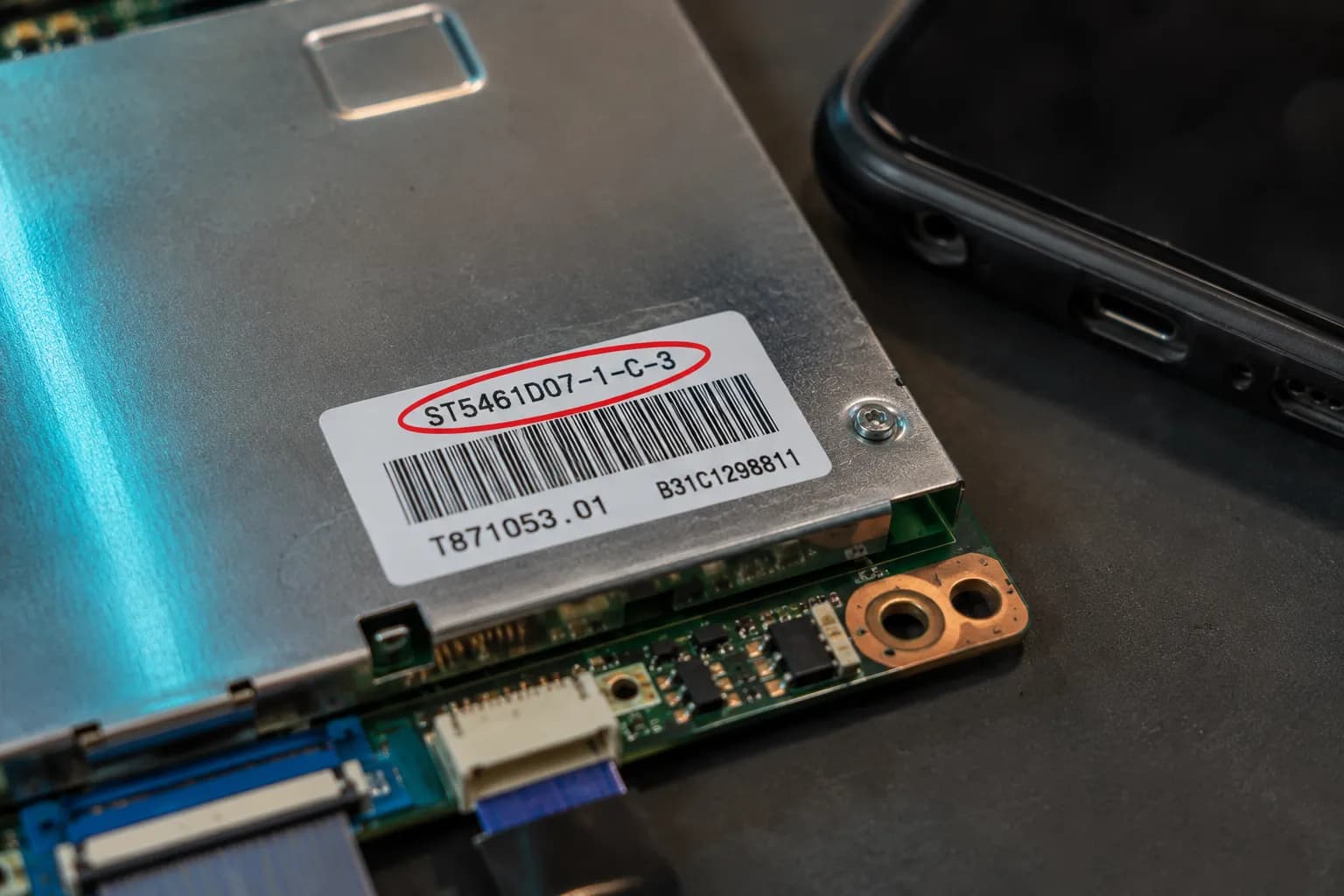 Part number sticker circled on a TV T-Con board for correct ordering.