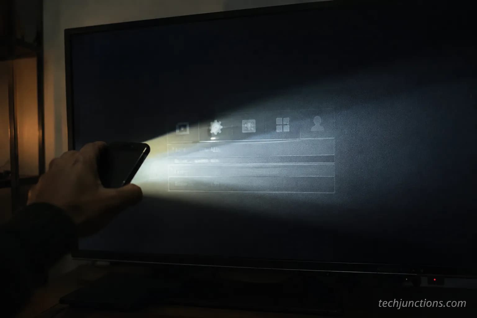 Phone flashlight raked across a black TV screen revealing a faint ghost image, confirming a backlight fault.