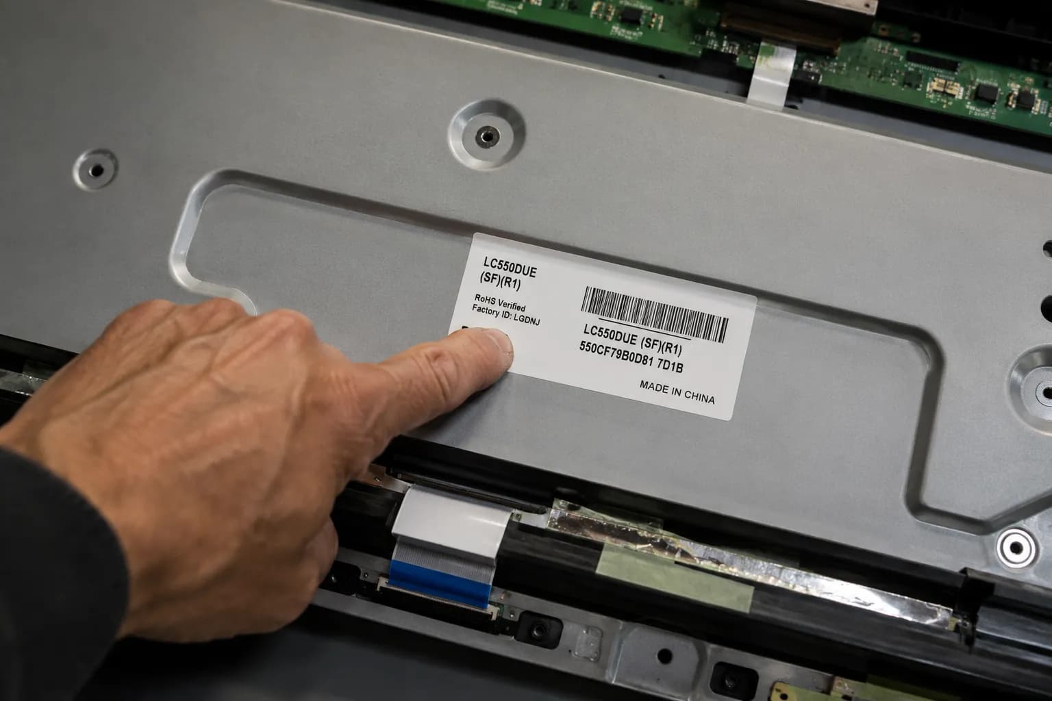 hand pointing to the part number sticker on a tv panel