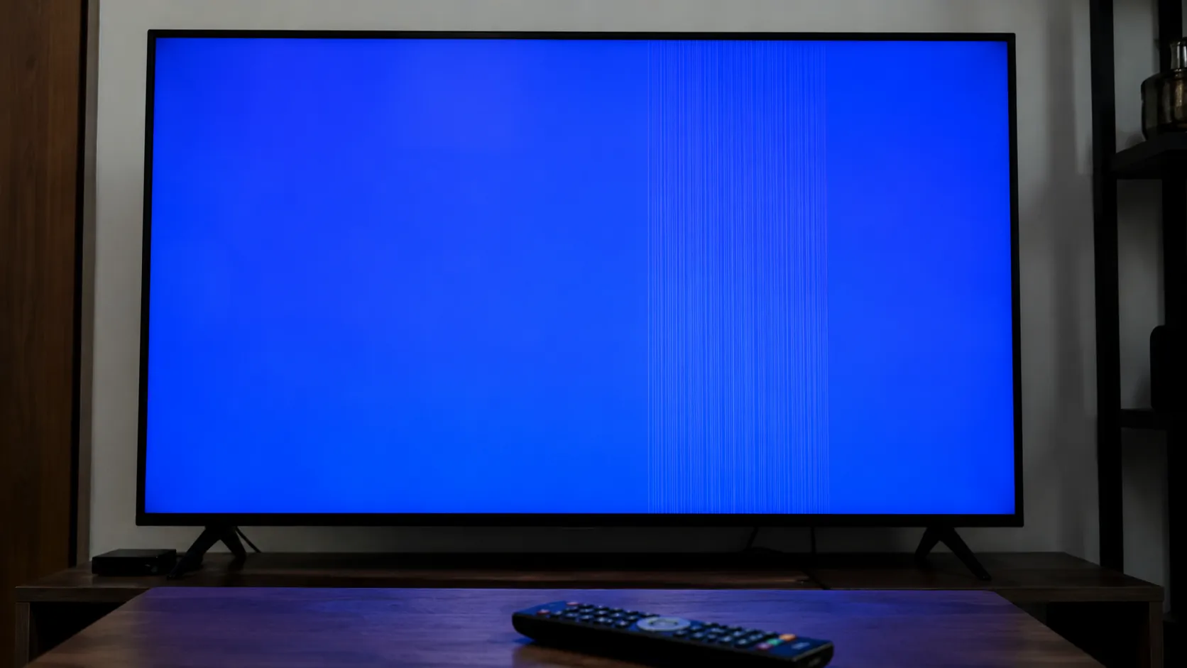 Flat-screen TV displaying a built-in picture test with a solid blue screen and persistent faint vertical lines, indicating a likely panel, ribbon cable, or T-CON display issue.