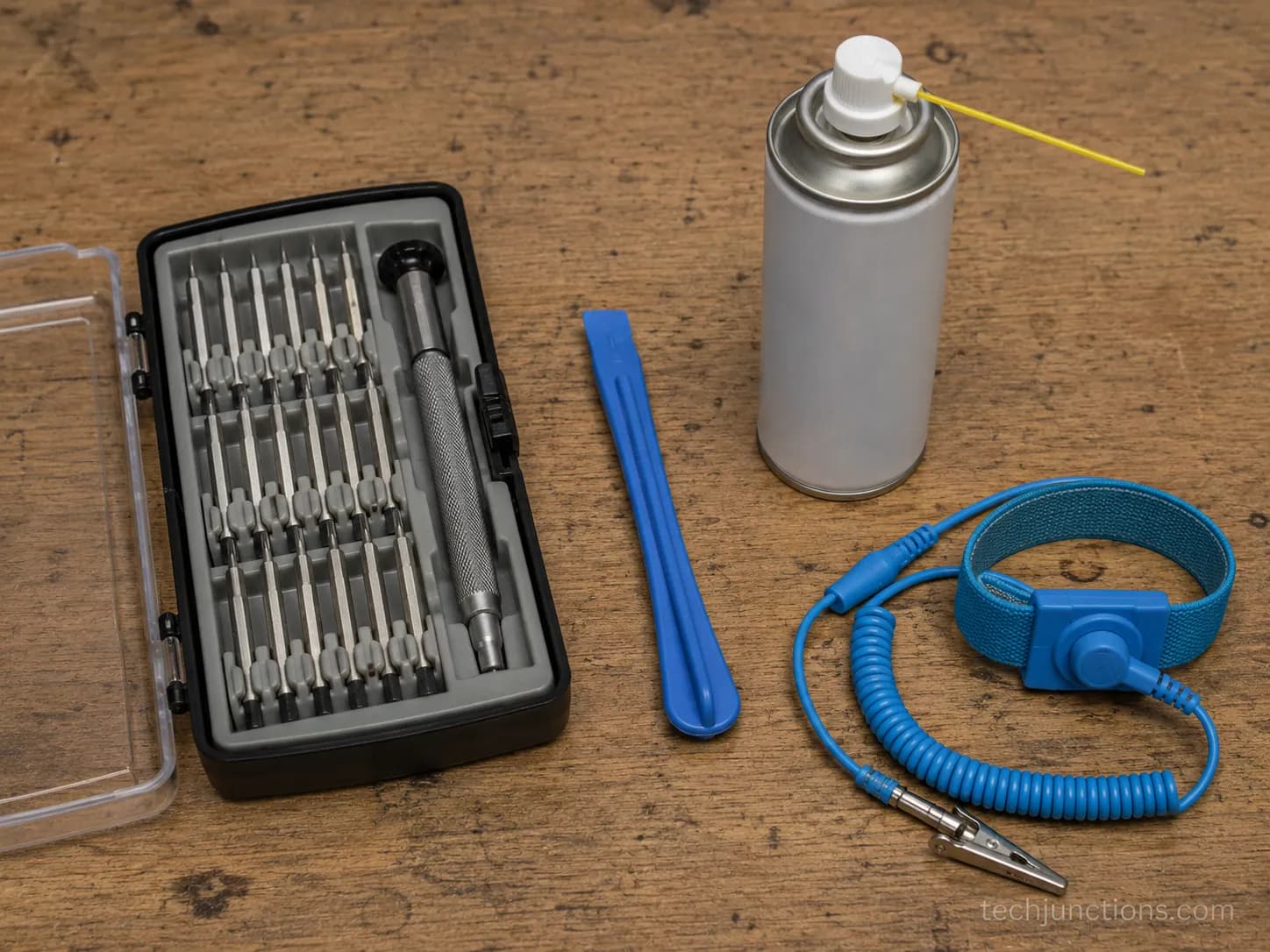 A TV repair tool kit with screwdrivers, a pry tool, contact cleaner, and an anti-static strap on a workbench.